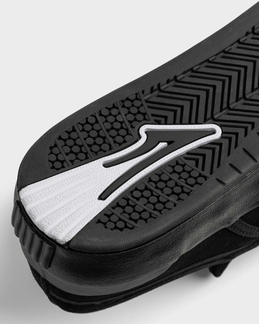 Close-up of a black and white athletic shoe sole with a brand logo on a light gray background