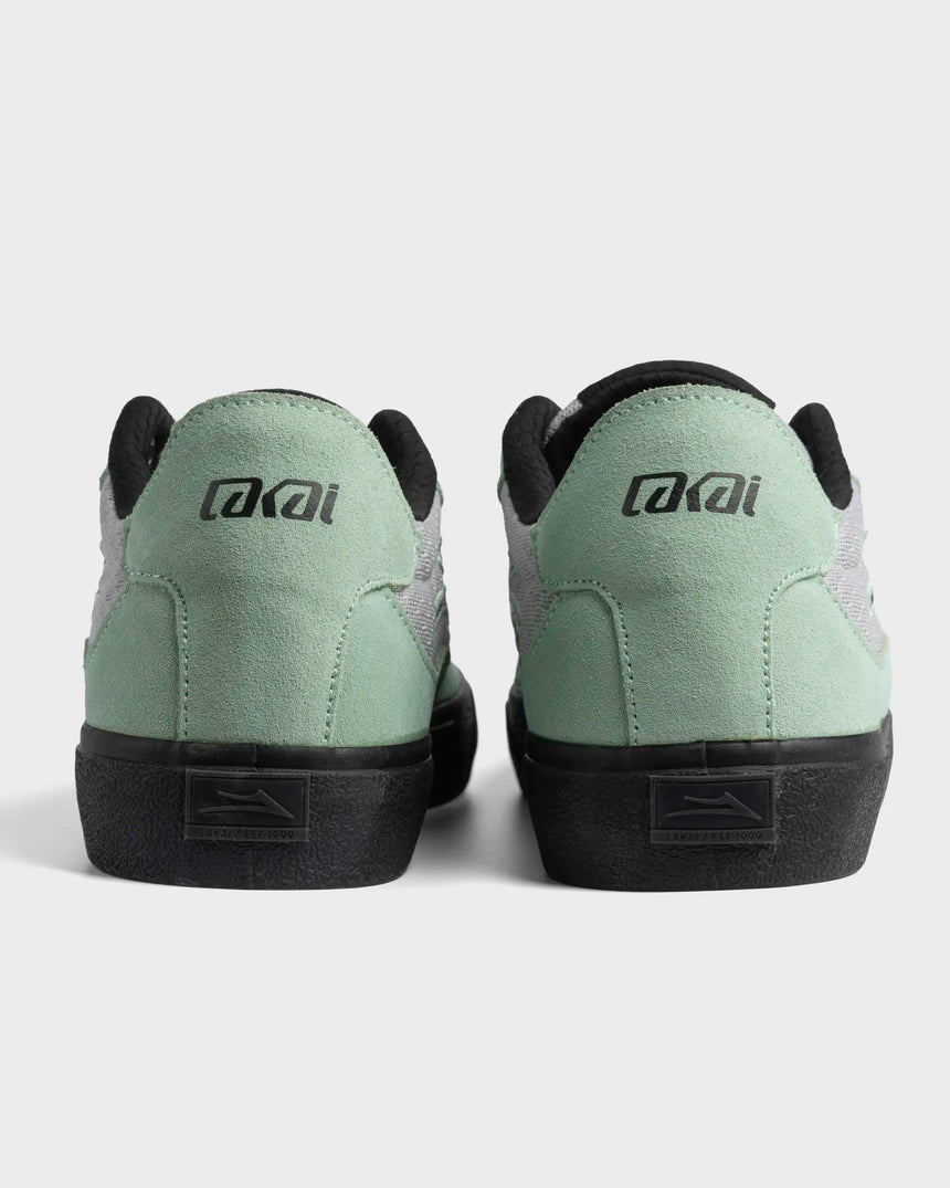Pair of green sneakers with black soles on a light gray background