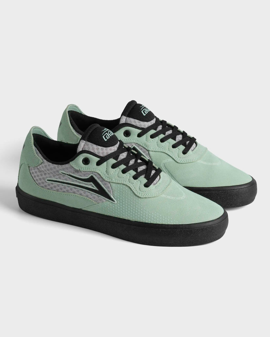 Pair of light green sneakers with black soles and laces on a white background
