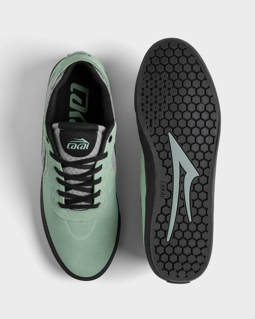 Green athletic shoe with black sole on a light gray background