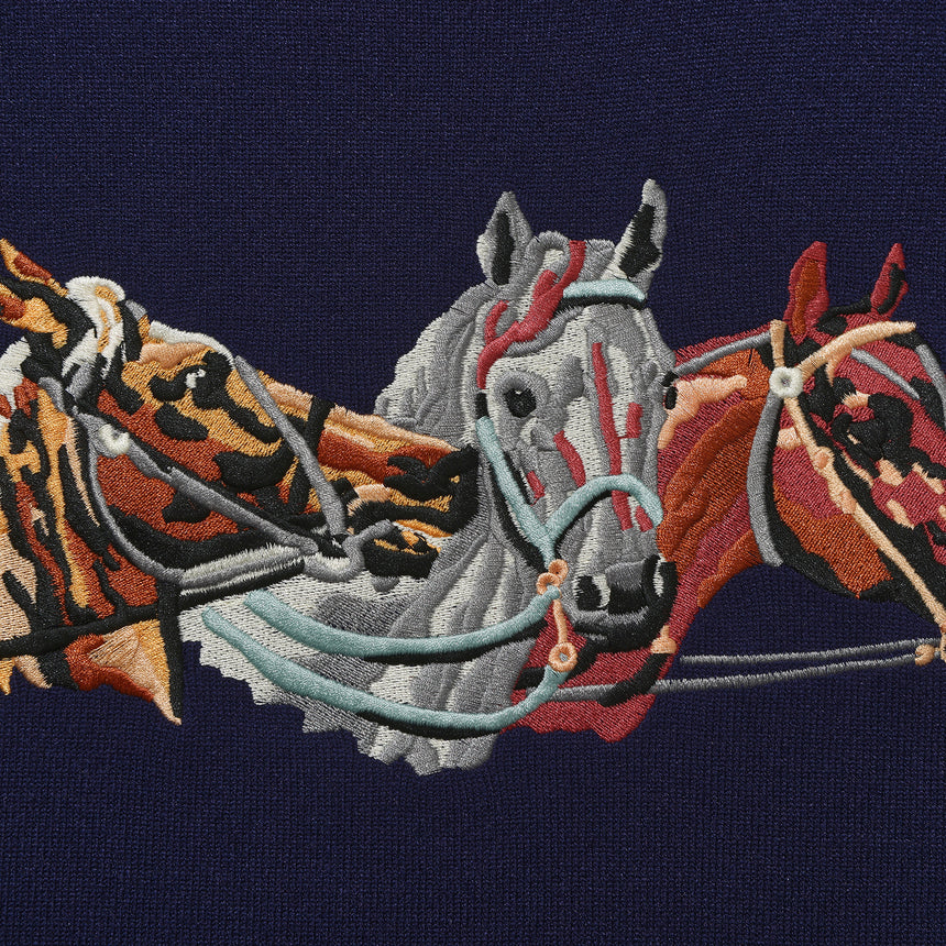 Embroidered design of three horses on a dark blue background