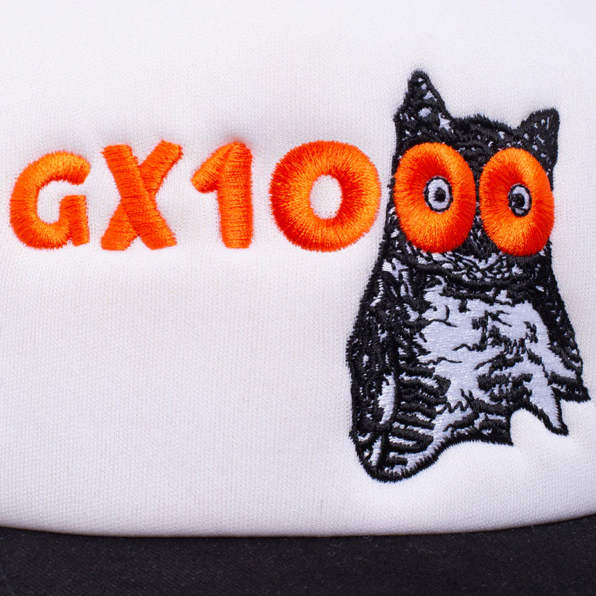White lens cap with an embroidered owl and 'GX100' text on a white background