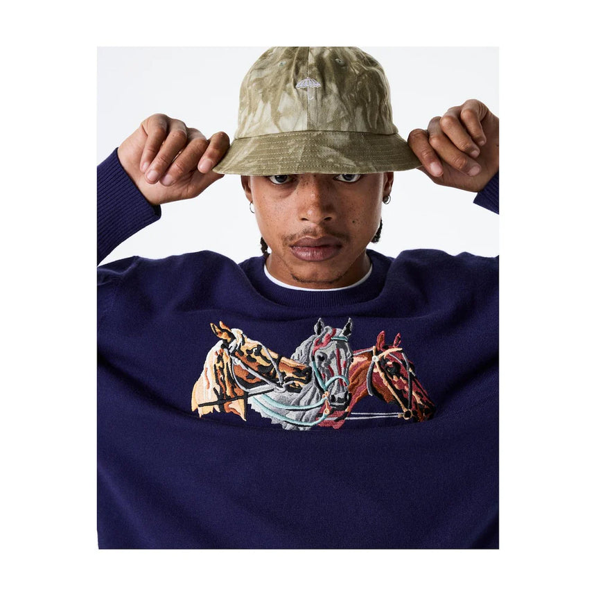Person wearing a navy blue sweatshirt with horse design and a camouflage bucket hat.