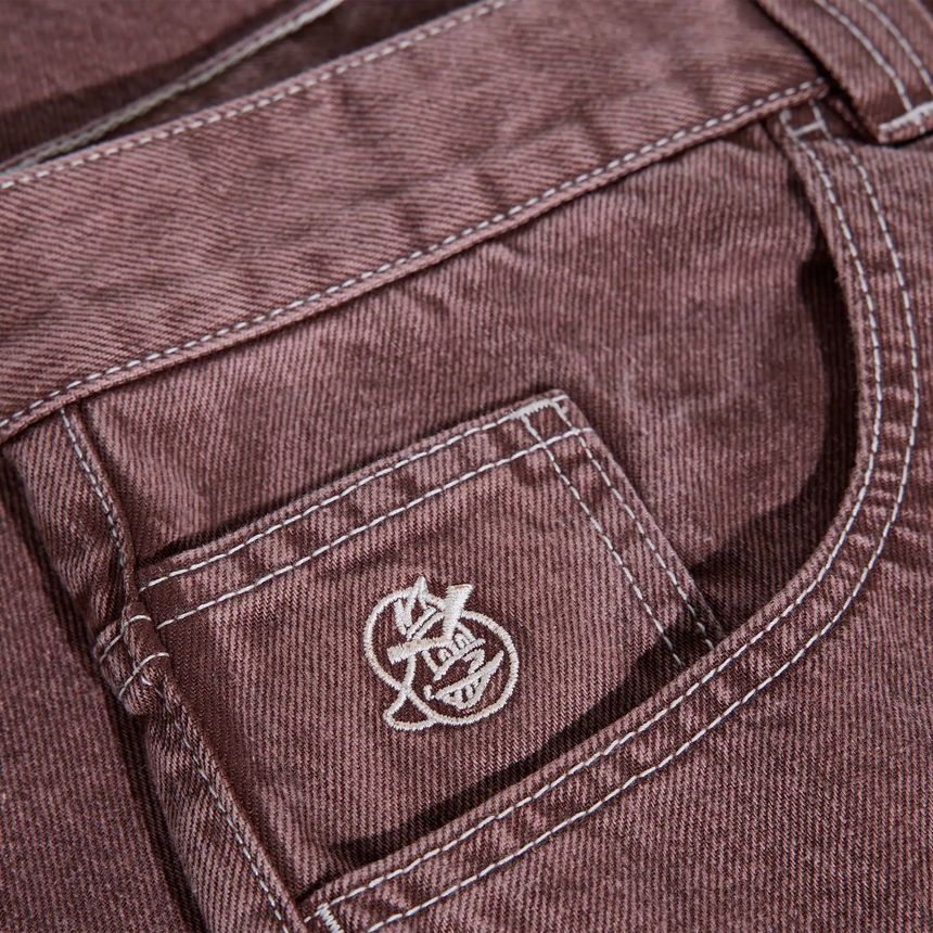 Close-up of a brown denim pocket with a logo on a garment.