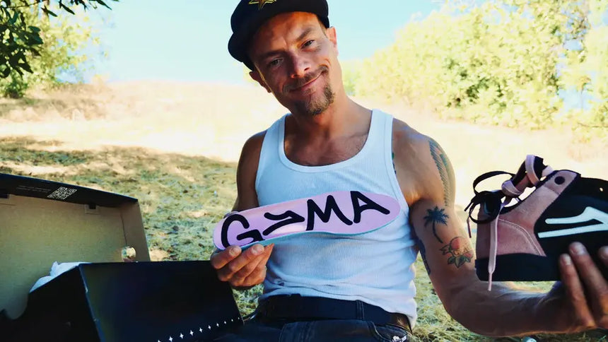 Man holding a pink sign with 'GAMA' on it, outdoors.