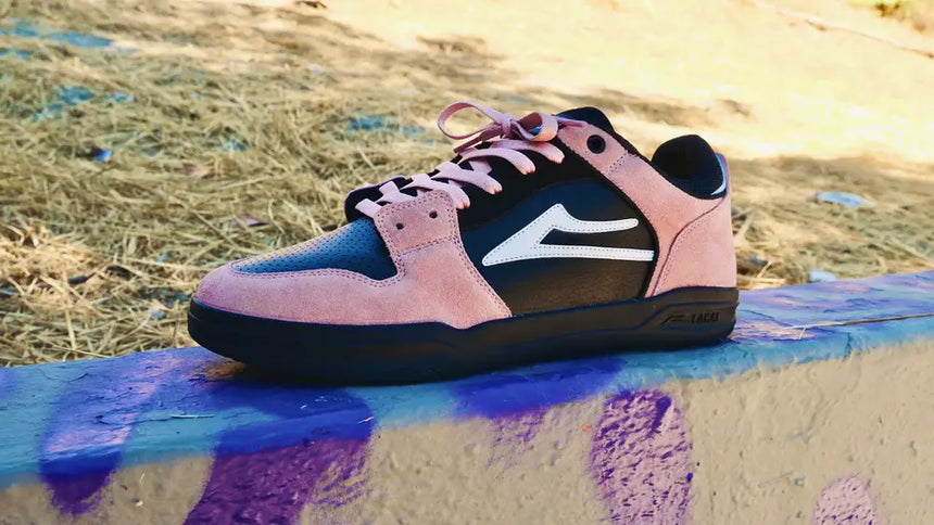 Pink and black sneaker with a white logo on a colorful concrete surface.
