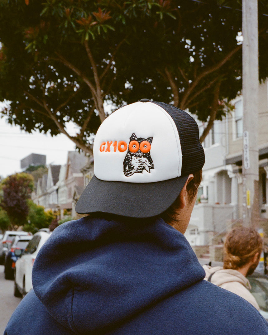 Person wearing a cap with a logo on a street
