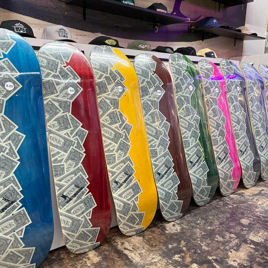 Row of colorful skateboard decks with patterned designs on a concrete floor.