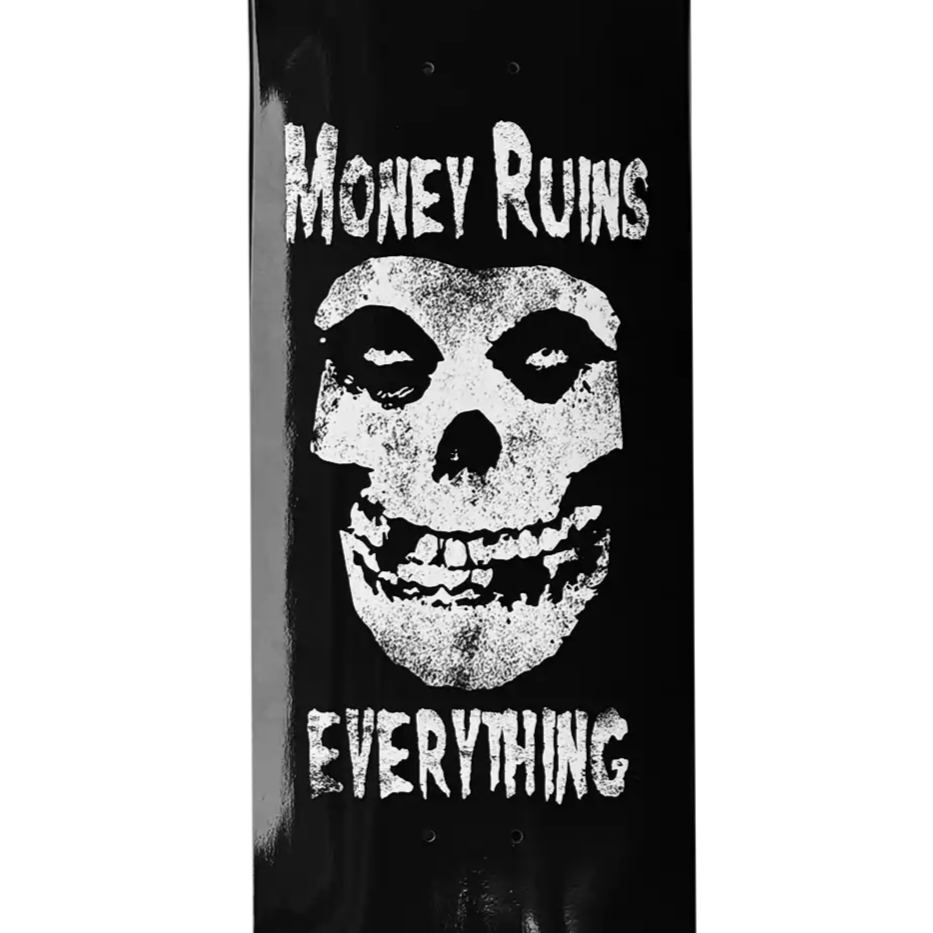 Skateboard deck with skull design and text 'Money Ruins Everything' on a black background