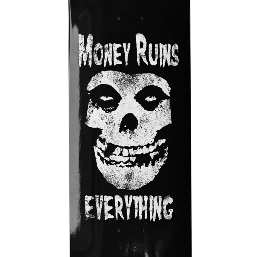 Skateboard deck with skull design and text 'Money Ruins Everything' on a black background