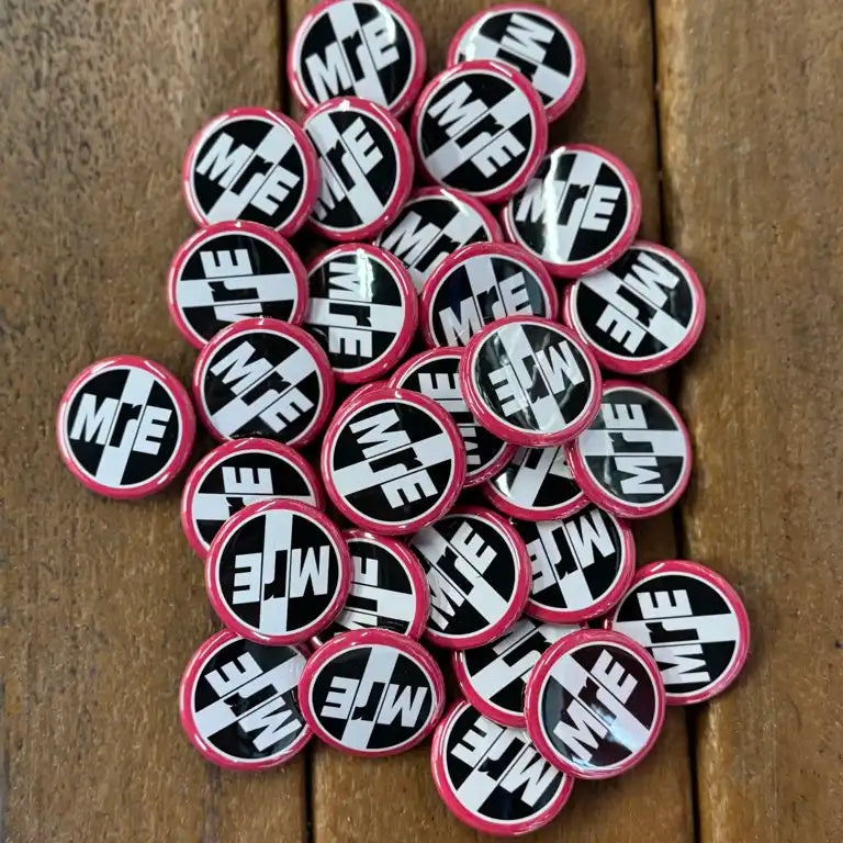 Collection of circular stickers with 'MJE' logo on a wooden surface