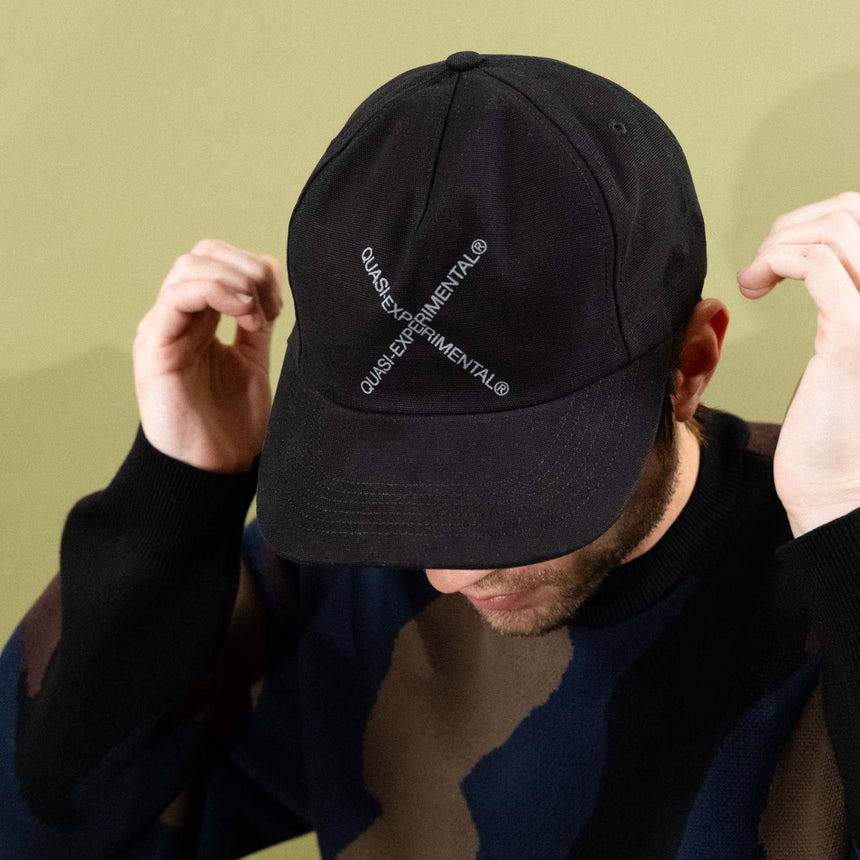 Person wearing a black cap with text on a green background