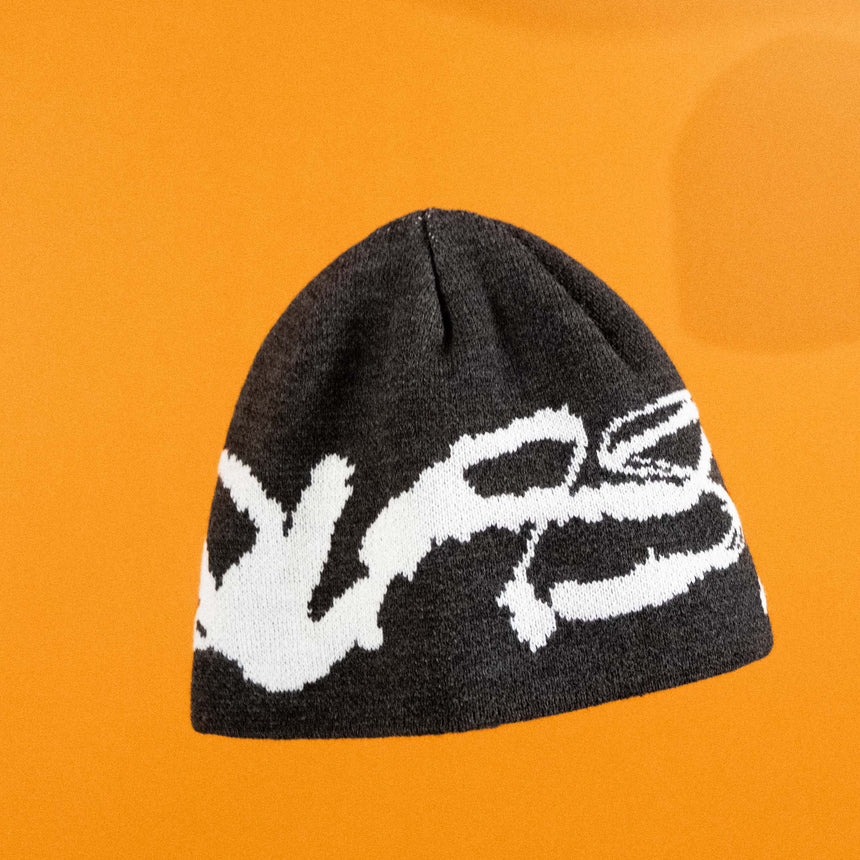 Black beanie with white logo on an orange background