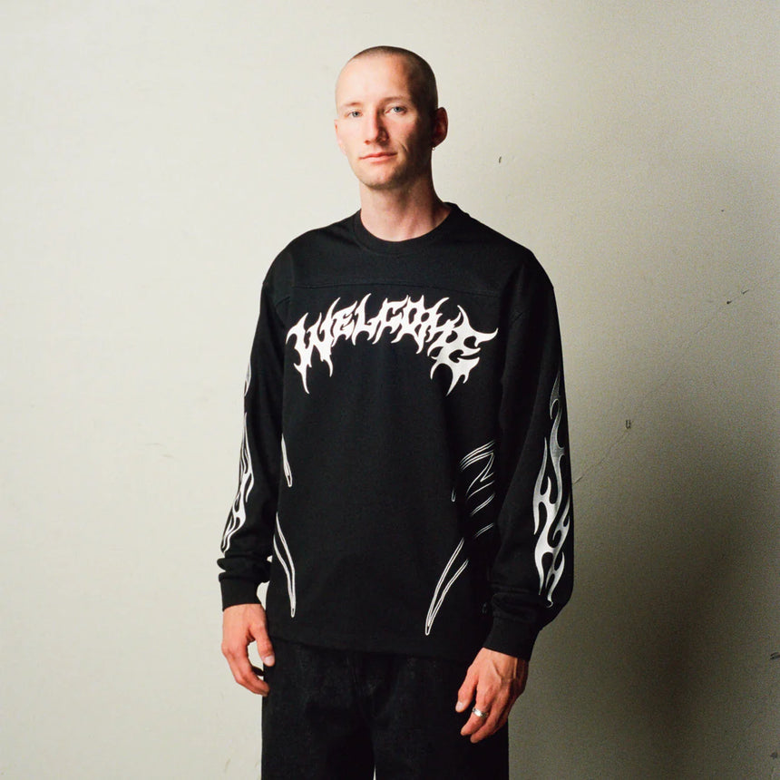 Person wearing a black long-sleeve shirt with white graphics against a plain background