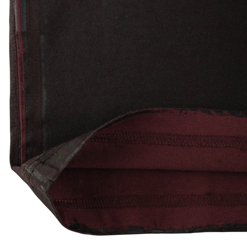 Close-up of a dark red fabric with a visible seam on a white background