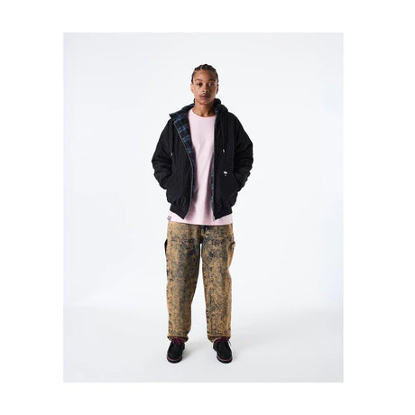 Person wearing a black jacket, pink shirt, and patterned pants on a white background