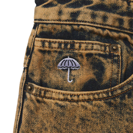 Close-up of a pocket with an embroidered umbrella design on a distressed denim background.