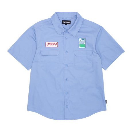 A short sleeve button down shirt in blue color with a collar, front pockets, and brand patches on the chest.