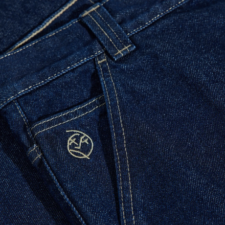 Close-up of blue denim fabric with a brand logo on a pocket