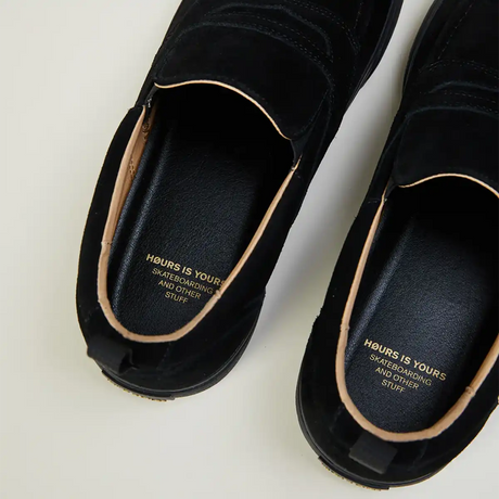 Black slip-on shoes with visible brand text on a light background