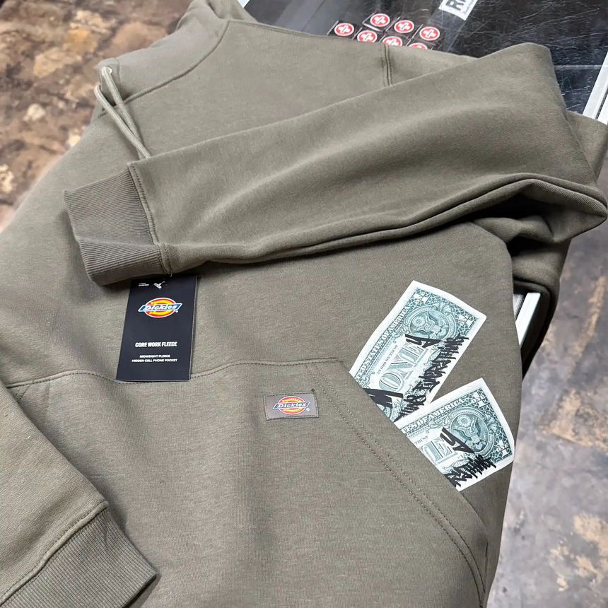 Folded green hoodie with Dickies branding on a textured surface