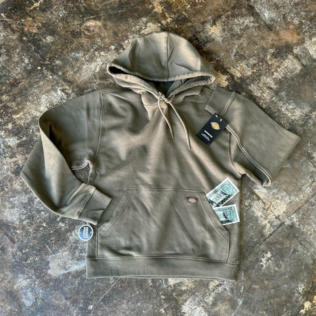 Green hoodie with tags on a textured surface