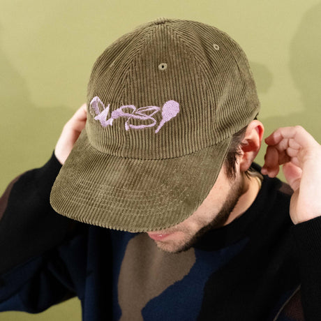 Person wearing a green cap with a logo against a green background